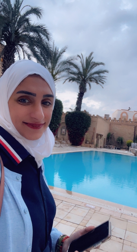       Selfie with a poolside view featuring an elegant building.
  