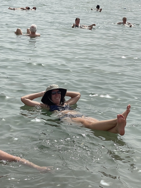 A person floating on the water's surface, possibly in the Dead Sea.
