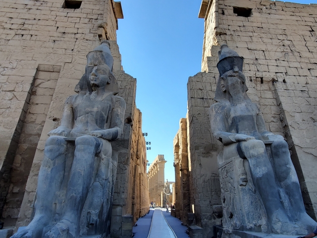 Close-up of two grand statues at the entrance of an ancient Egyptian temple.
