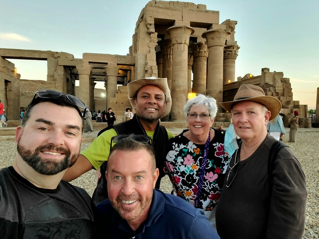 Tourists posing in front of ancient Egyptian ruins.
