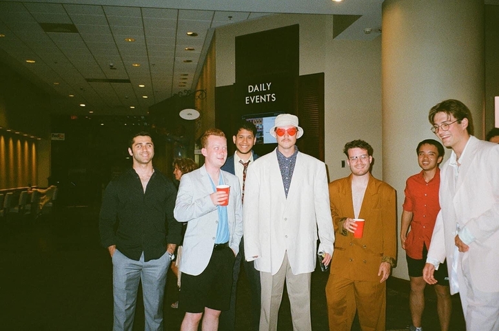 A group of people indoors with drinks, dressed casually.