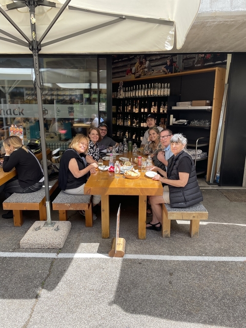 Group of people enjoying a meal at a table outdoors.