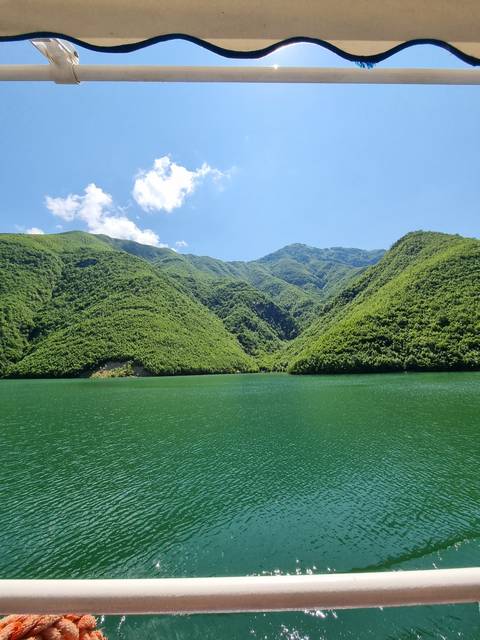 Green mountains next to a calm lake.