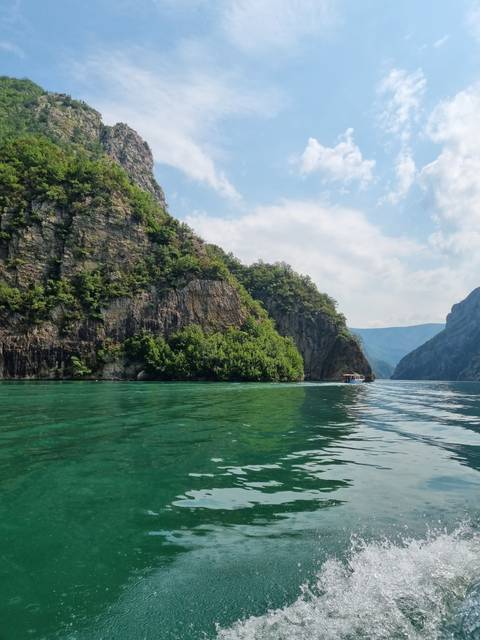       Rocky cliffs with green water and sky.
  