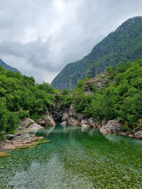 Calm waters surrounded by rocky cliffs and greenery.