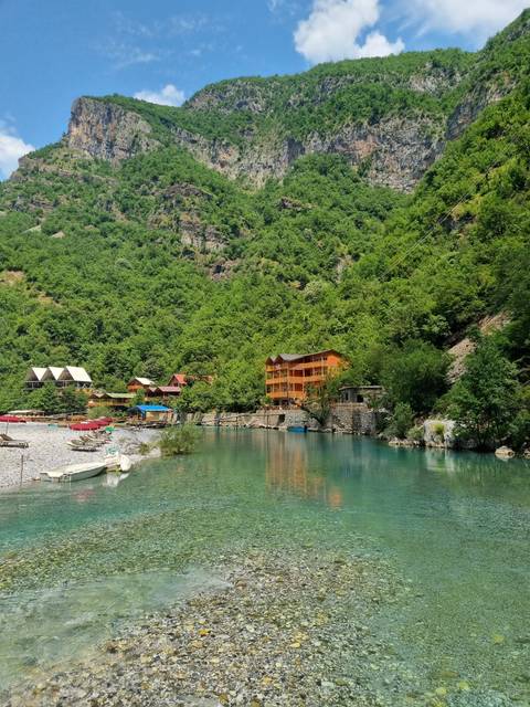 Building by a lake with rocky, mountainous surroundings.