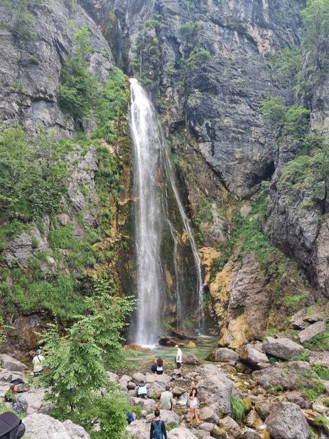 Waterfall cascading down a rock face with people nearby.