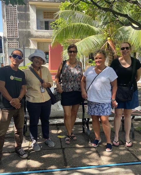 Group of people posing outdoors by trees.