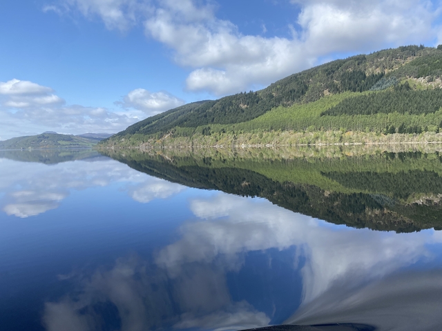       Pristine lake reflecting the surrounding forest and clouds.
  