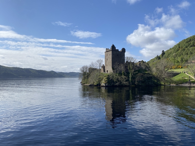       Historic castle overlooking a serene lake surrounded by hills.
  
