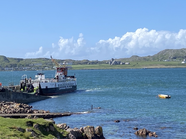       Ferry docked at a port with scenic hills in the background.
  