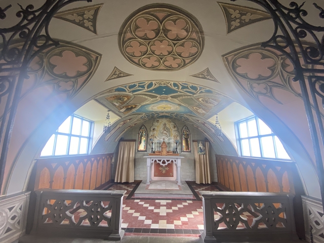       Decorated interior of a chapel with stained glass windows.
  