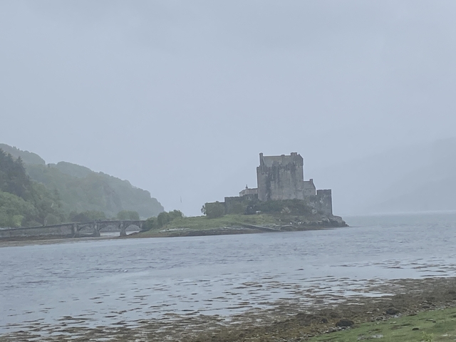       Castle on a small island surrounded by water under cloudy skies.
  