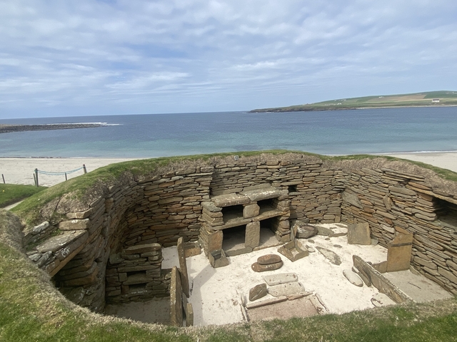       Ancient stone structure with grassy ceiling by the beach.
  