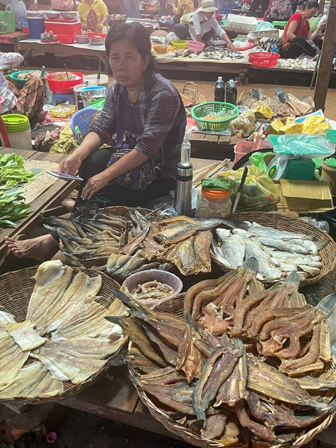       Market vendor with baskets of fish.
  