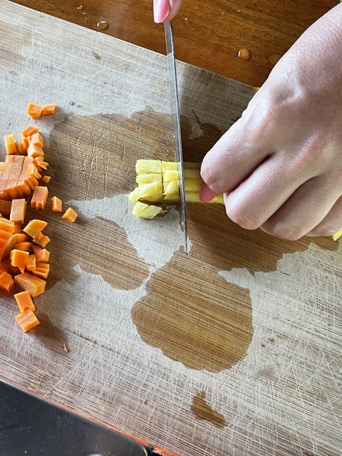       Hand chopping vegetables on cutting board.
  