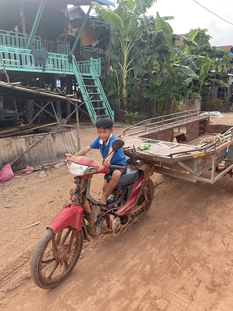       Child riding a motorbike in a village.
  