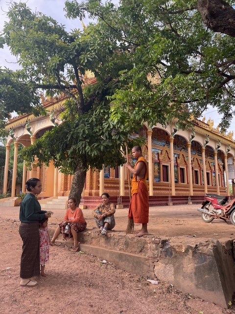       Monk and people outside decorative temple.
  