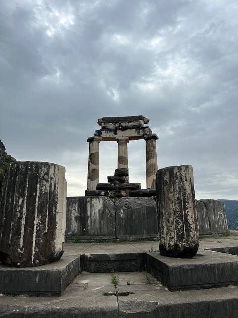 Ancient ruins with columns against a cloudy sky, possibly a temple.