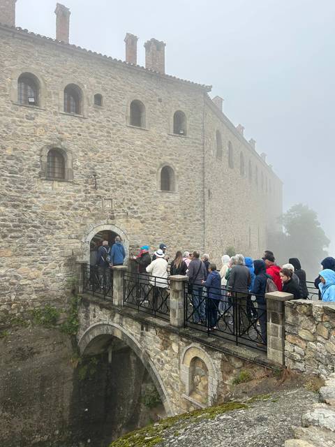 A group of people on a foggy day outside a historic stone building.