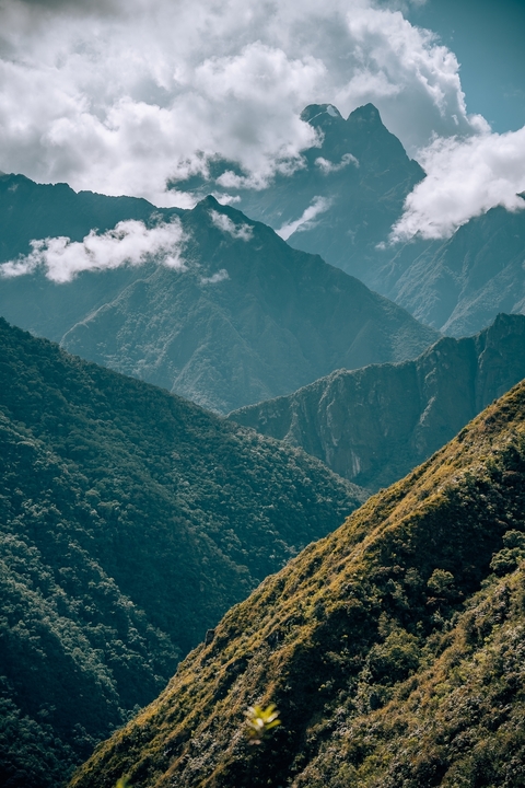Mountain ranges with lush greenery under a cloudy sky.