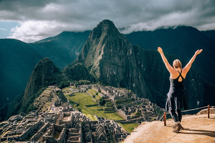 Person raising hands with Machu Picchu in the background.