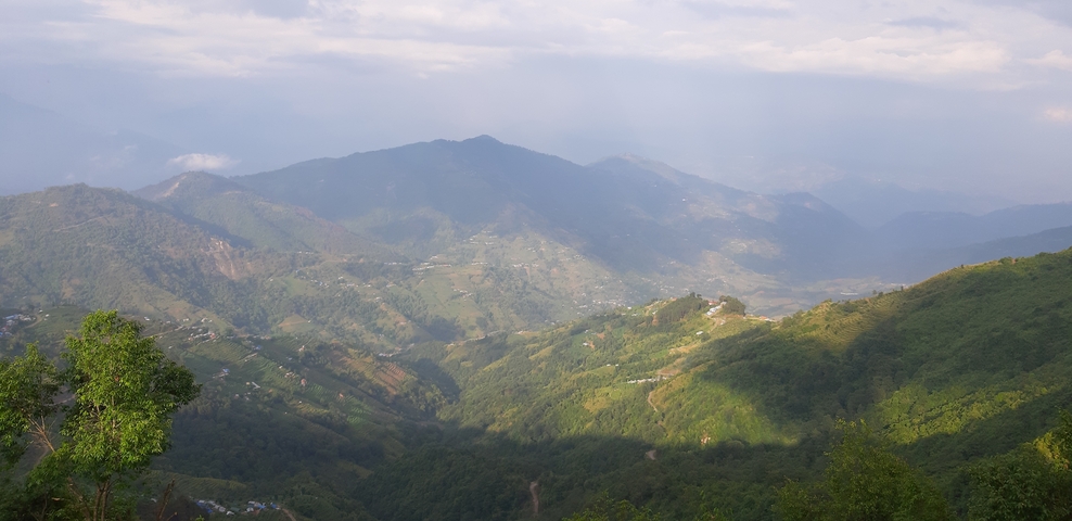       Landscape of lush green mountains under a cloudy sky.
  