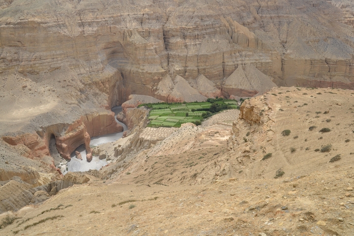 A valley with rocky cliffs and patches of vegetation.
