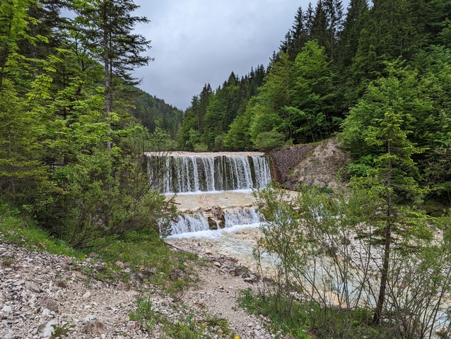       Cascading waterfall amidst a forest, with rocky surroundings
  
