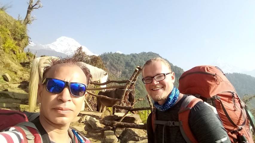       Two hikers with backpacks and a mountain view in the background
  