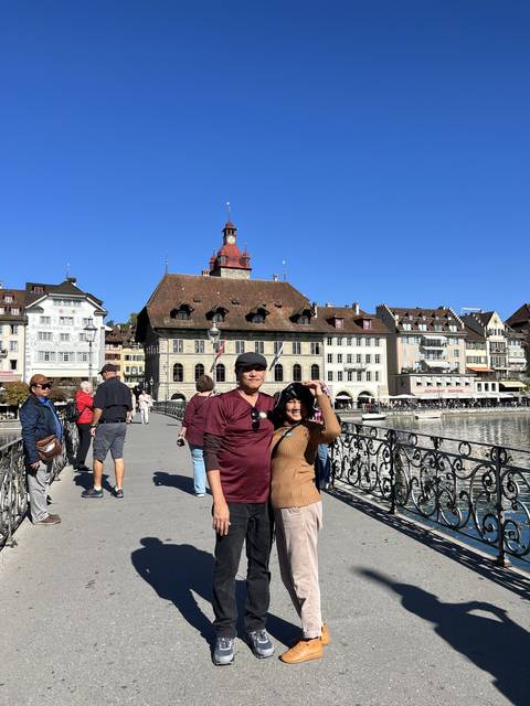       Tourists standing on a bridge with historic cityscape.
  