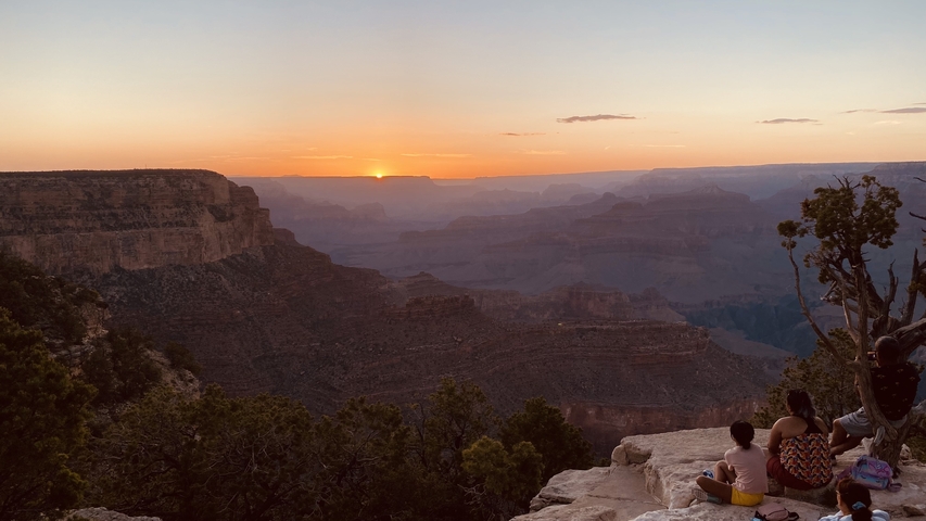 Sunset view over the Grand Canyon with people sitting.