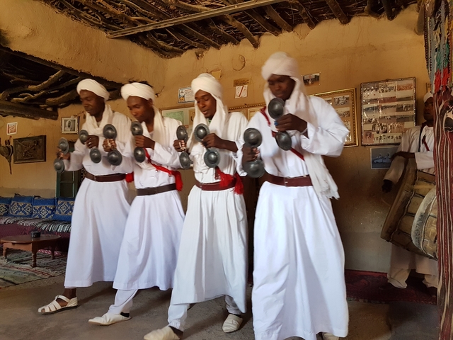       Musicians in traditional attire performing indoors.
  