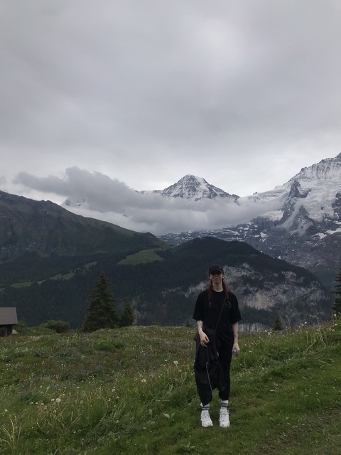A person standing with a mountainous landscape in the background.