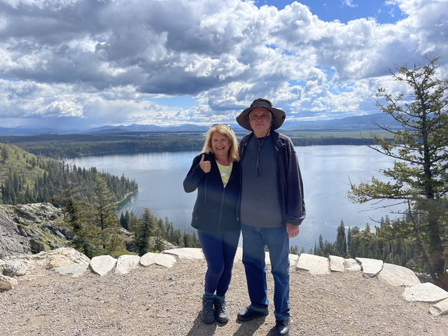Couple posing with a stunning view of a lake and mountains.