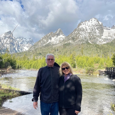 Couple posing with mountains and a river in the background.