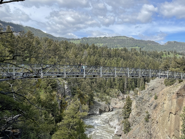 Couple on a bridge over a gorge with a scenic backdrop.