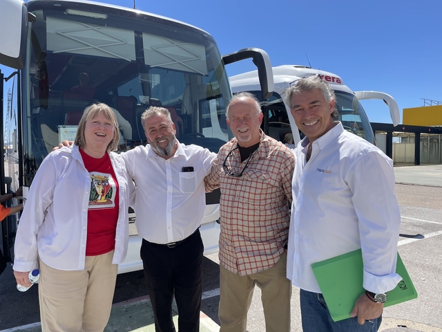       Four people standing in front of a tour bus.
  