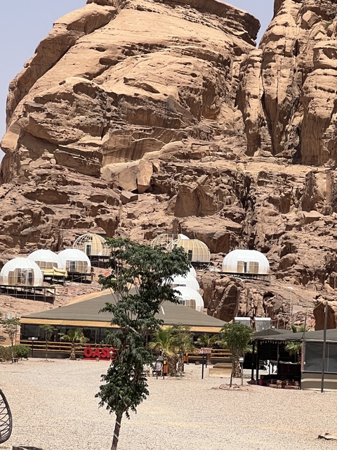 Luxury camp with domed tents set against a rocky mountain.