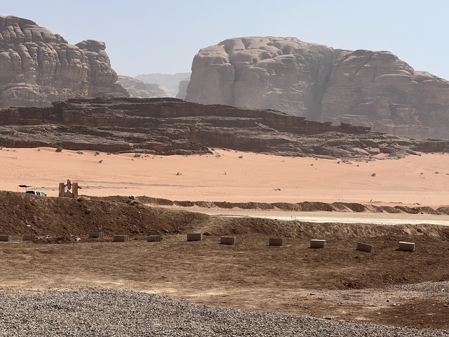 Expansive desert landscape with rocky cliffs in the distance.