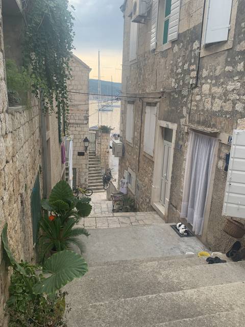 Narrow street with stone buildings and a glimpse of water.