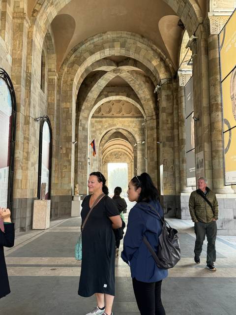 People walking under an ornate archway with architectural details.