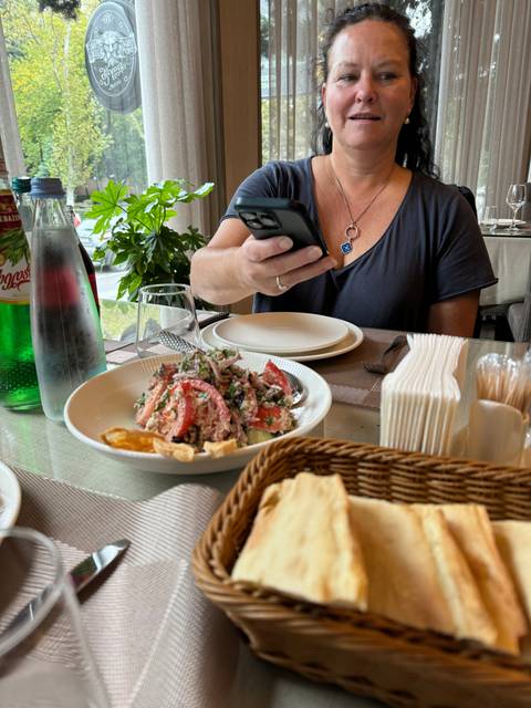 Woman dining at a table with a smartphone in hand.