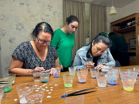       Women painting glasses at a craft workshop.
  