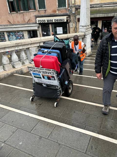 A porter with luggage near stairs.