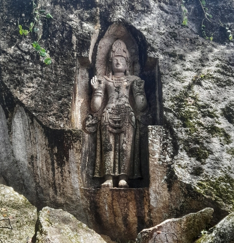       Ancient carved figure in rock wall.
  