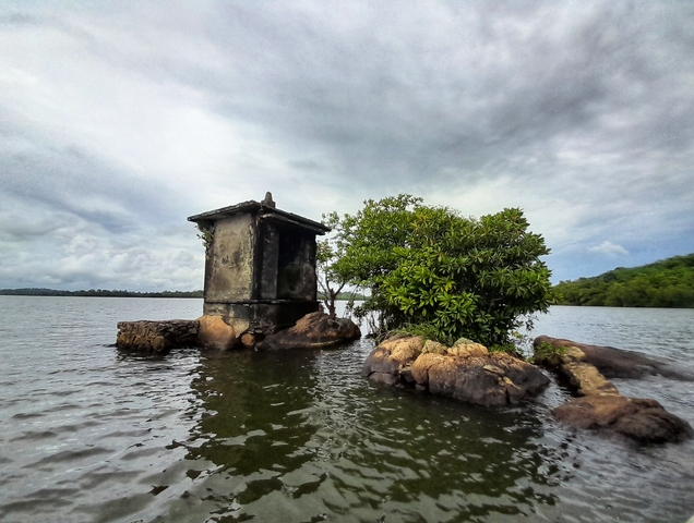       Small structure surrounded by water and trees.
  