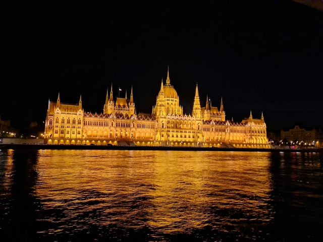 Illuminated parliament building with reflection in water.