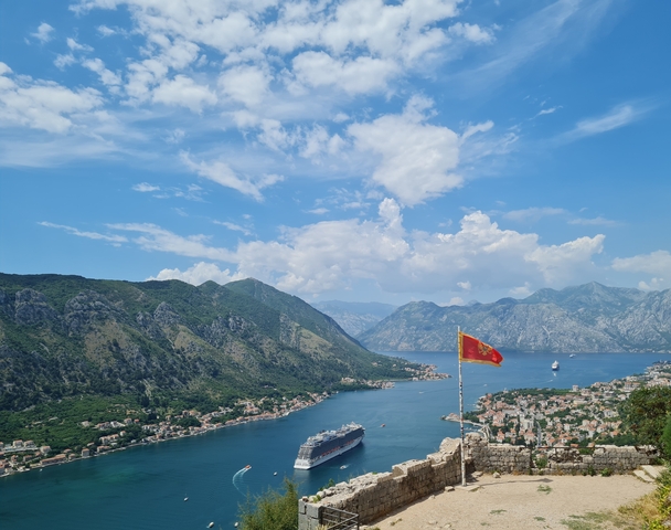 Coastal view with Montenegro flag and mountains.