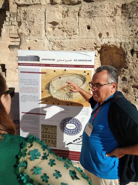 Man pointing at an information board outside a historic site.